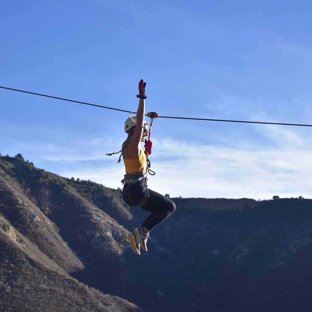 woman on a zipline high above in the mountains